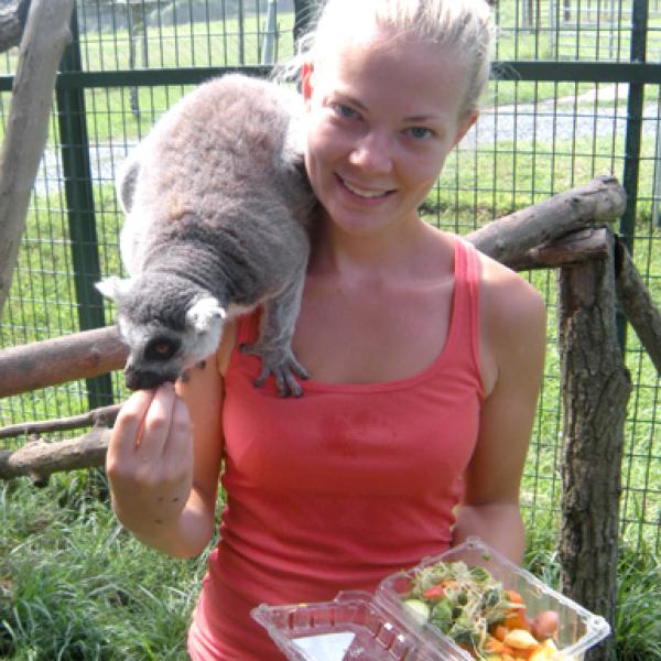 A female student holding an animal at a zoo