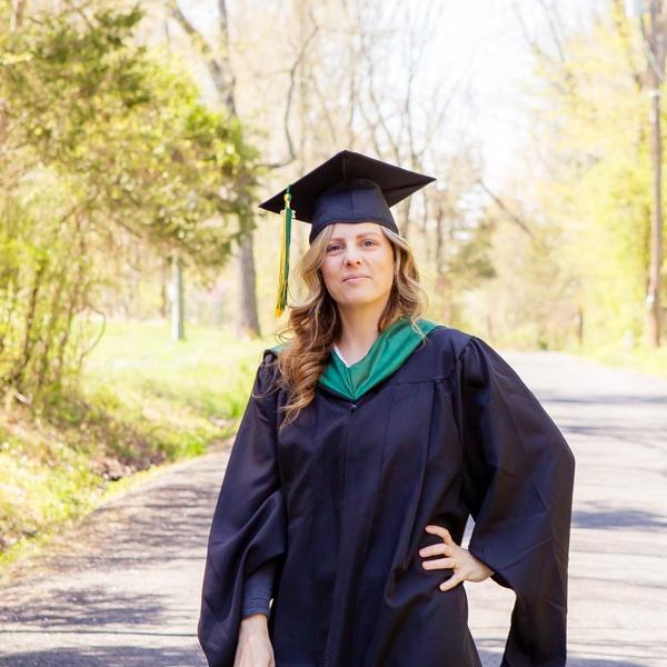 A woman in a cap and gown posing on a pathway