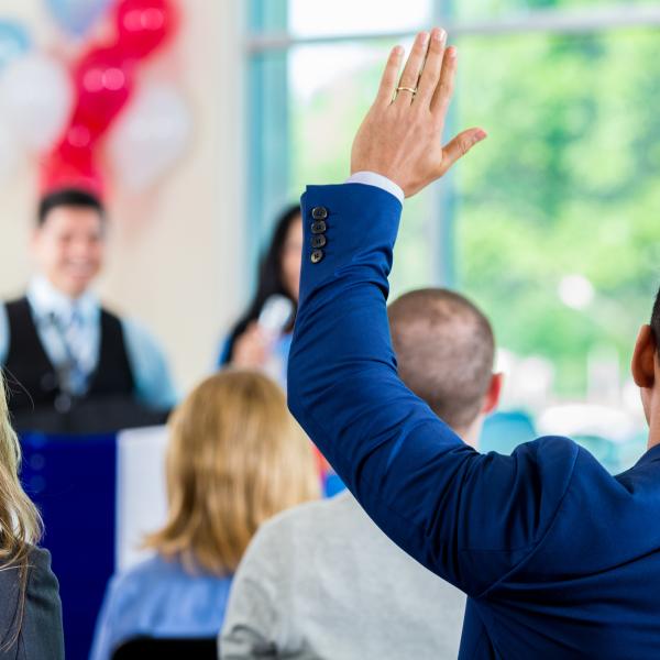 A gentalman in a crowd raising his hand.