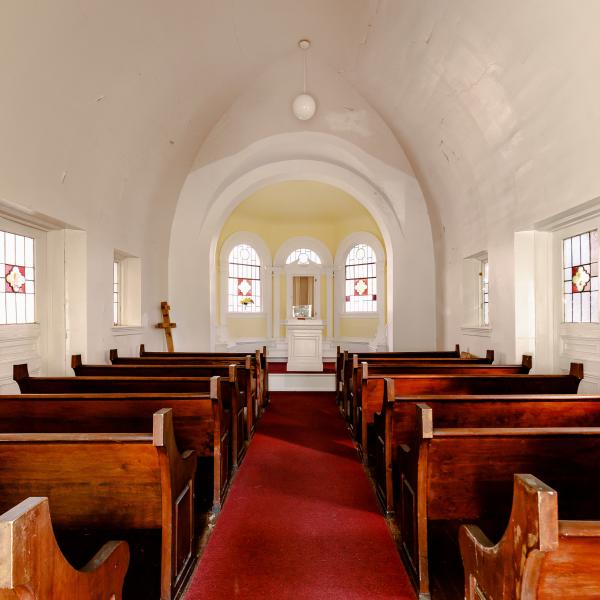 the chapel's interior view from the rear of the room showing the pews and alter