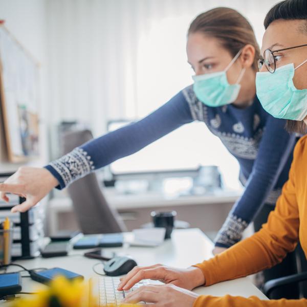 two women at the computer wearing masks