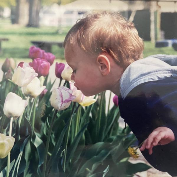 a baby sniffing flowers