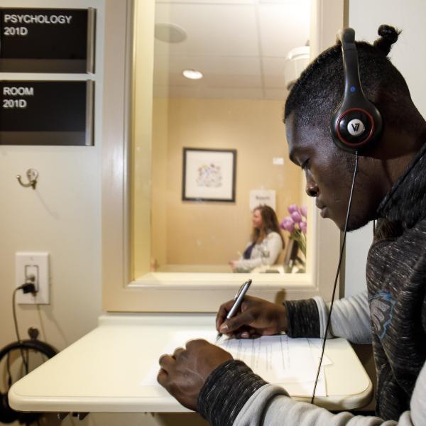 A psychology student is writing with head phones on