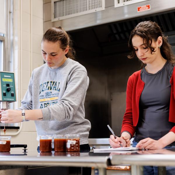 Two Food Science students are testing liquids in beakers. 