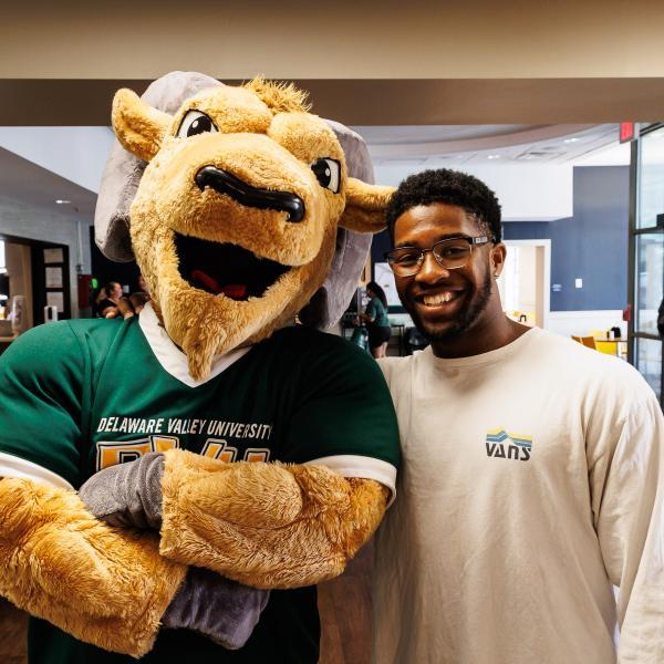 Caesar the mascot with a smiling student in the dining hall. 