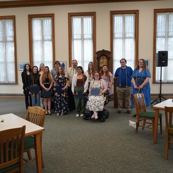 A picture of a group of students wearing honor society cords after being inducted in the library. 