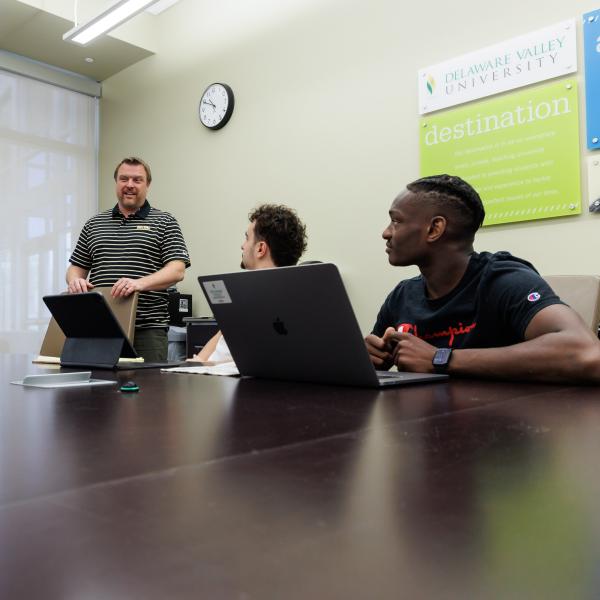 Business and Information professor Jeff Wehrung is with two students in a conference room. 