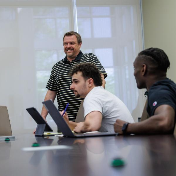 Jeff Wehrung in a conference room with students who are talking with him. 