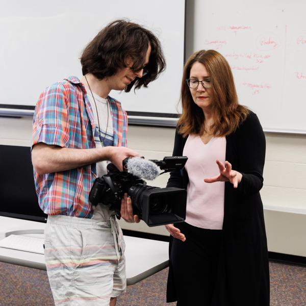 Marion Callahan with a student using a video camera.
