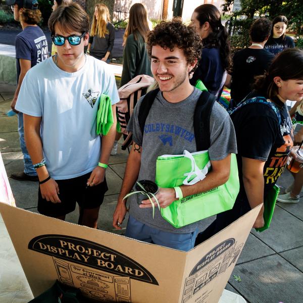 A student is at the clubs and orgs expo talking with a student about a club.