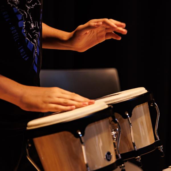 A student is playing the drums in the life sciences building auditorium.