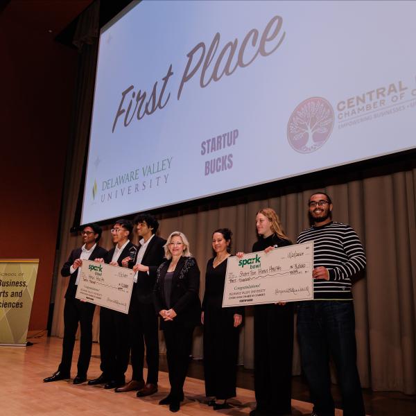 Spark Bowl Winners are onstage holding a giant check.