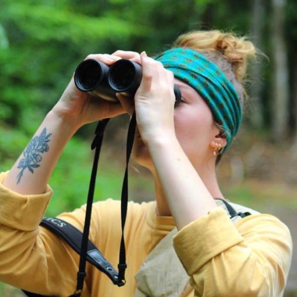 A female student is in costa rica with binoculars. 