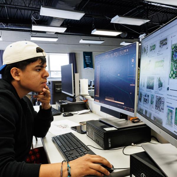 A student is in the landscape design studio facing a computer while operating a design software. 