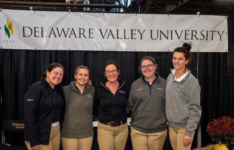 Students involved in the yearling sale stand side by side for a photo in front of a Delaware Valley University banner. 