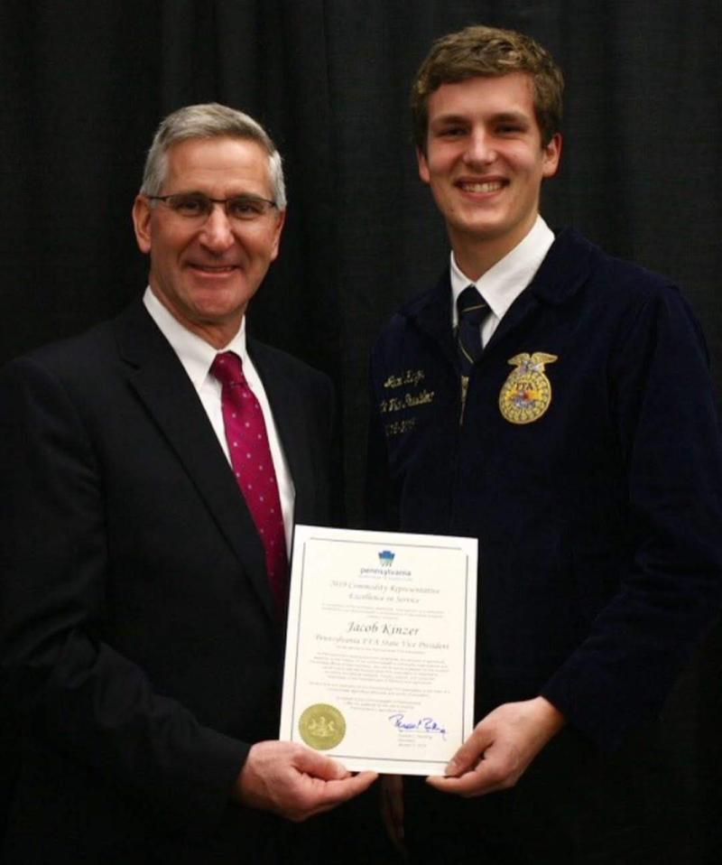 Russell Redding, Secretary of Agriculture, and Jacob Kinzer, DelVal student Agriculture Ambassador are side by side holding a certificate together. 