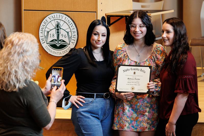 Three students pose for the camera while holding a certificate. 