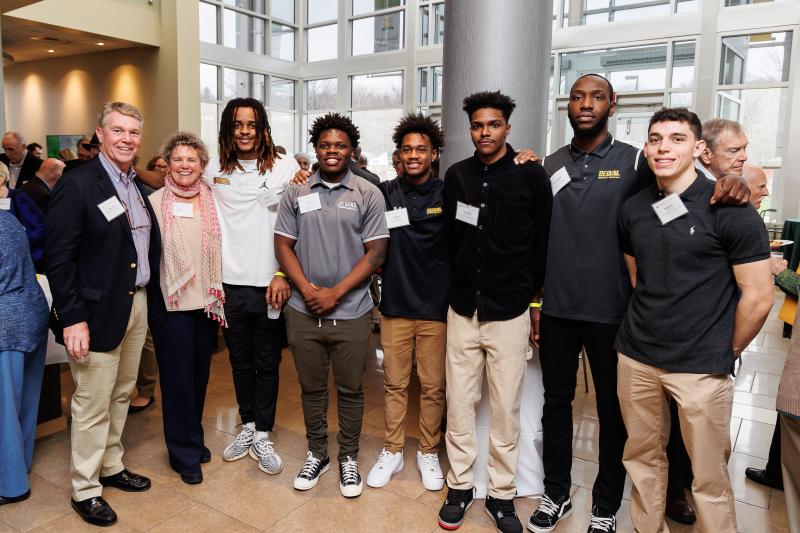 Several student athletes are posed with scholarship donors in the Life Sciences Building Atrium. 