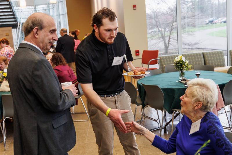 Student Wyatt Hoffman '22 is shaking hands with a scholarship donor. 