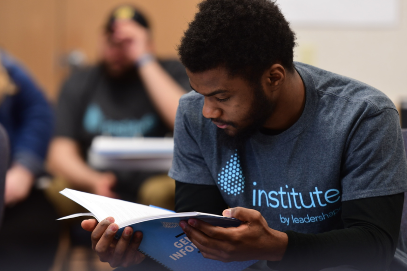 A student is seated while reading from a workbook. 