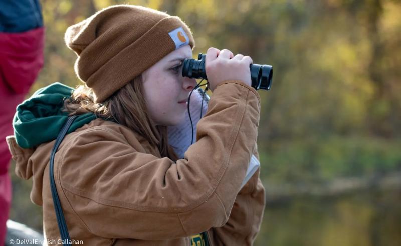 A student using binoculars to bird watch 