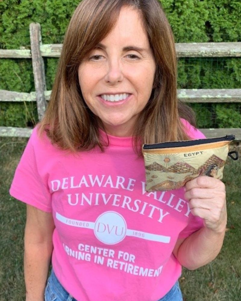 A CLR Member is wearing a pink CLR shirt holding up an egypt coin purse.