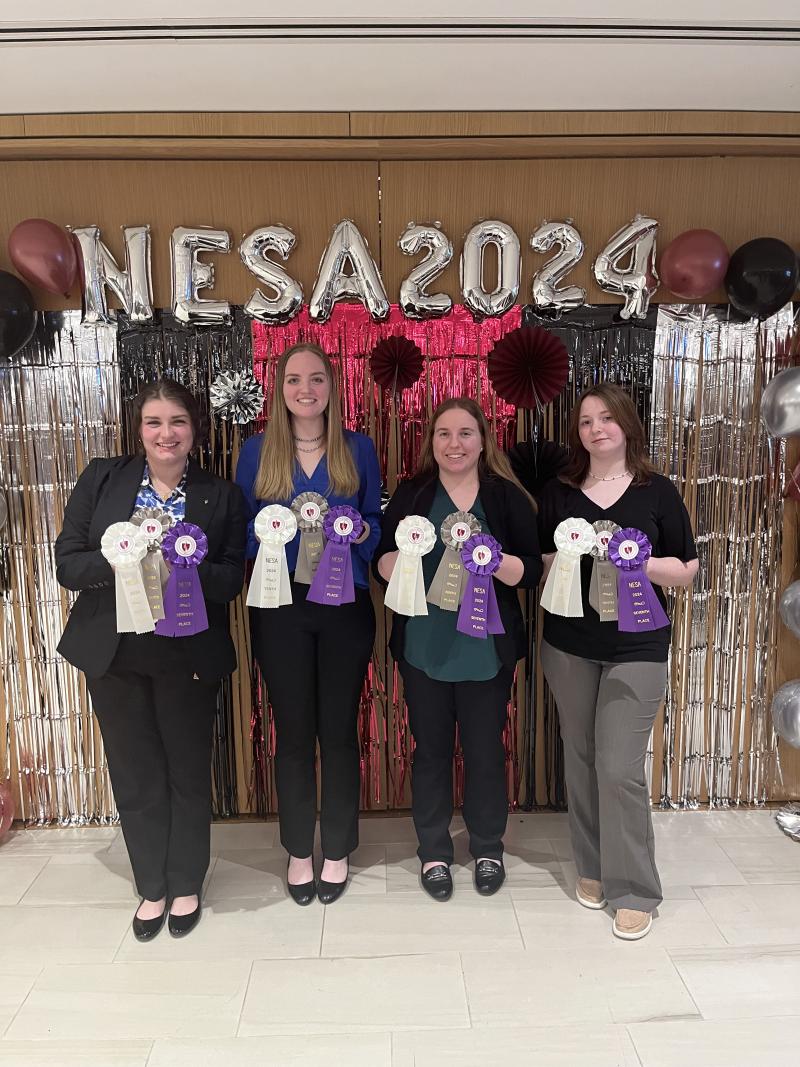 A group of four women holding up three different colored ribbons. 