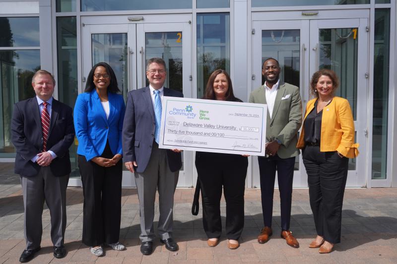 DelVal Staff and Penn Community Bank Staff are posing together with a giant check in hand. 