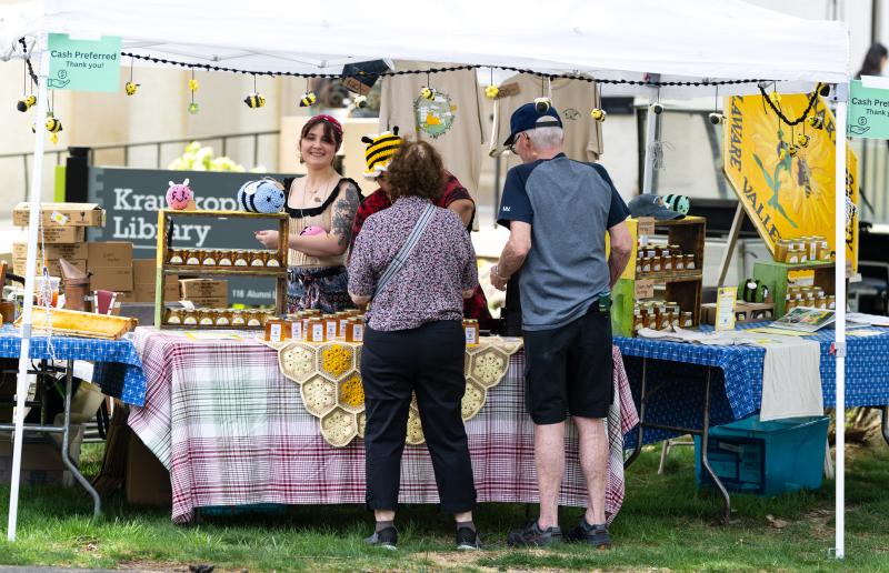 Two adults stand at a vendor table being helped by a student working the table.