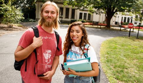A smiling male and female student on their way to class. 