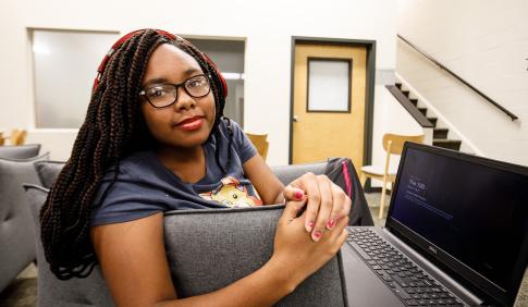 African- American female student sitting in lounge with her laptop. 