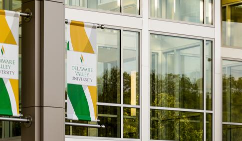 Photo of building on campus with colorful DelVal flags hanging.