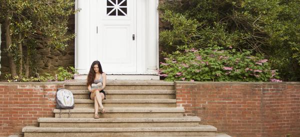 Student reading book on stairs in front of the chapel 