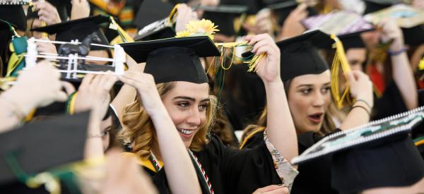 A female graduate moving her tassel at commencement.