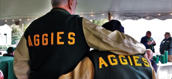 Two alumni embrasing wearing Aggies leterman jackets