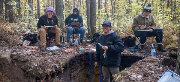 Students are in a soil pit working with analysis tools.