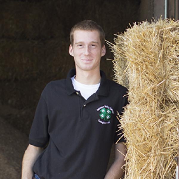 A student leans against a haystack