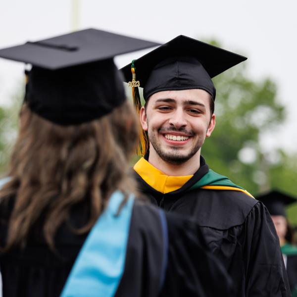 Student at graduation wearing cap and gown. 