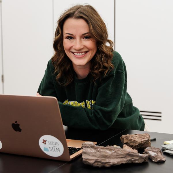 Madison Osatchuk '23 on her laptop surrounded by rocks. 