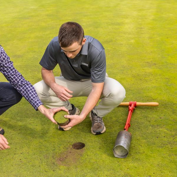 A student is creating a hole in the turf at a renowned golf course.