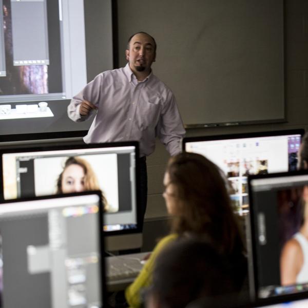A back of class view of media and communication students in the media lab working with mac computers.