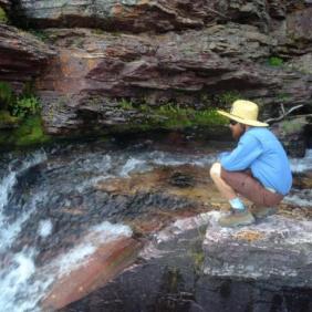 Student Zac Haynes kneeling near waterfall.