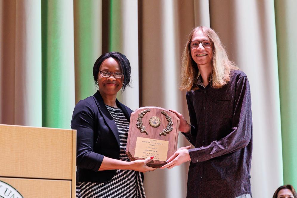 Smith Easton is on stage at the LSB auditorium receiving an award from Dr. Gloria Oikelome.