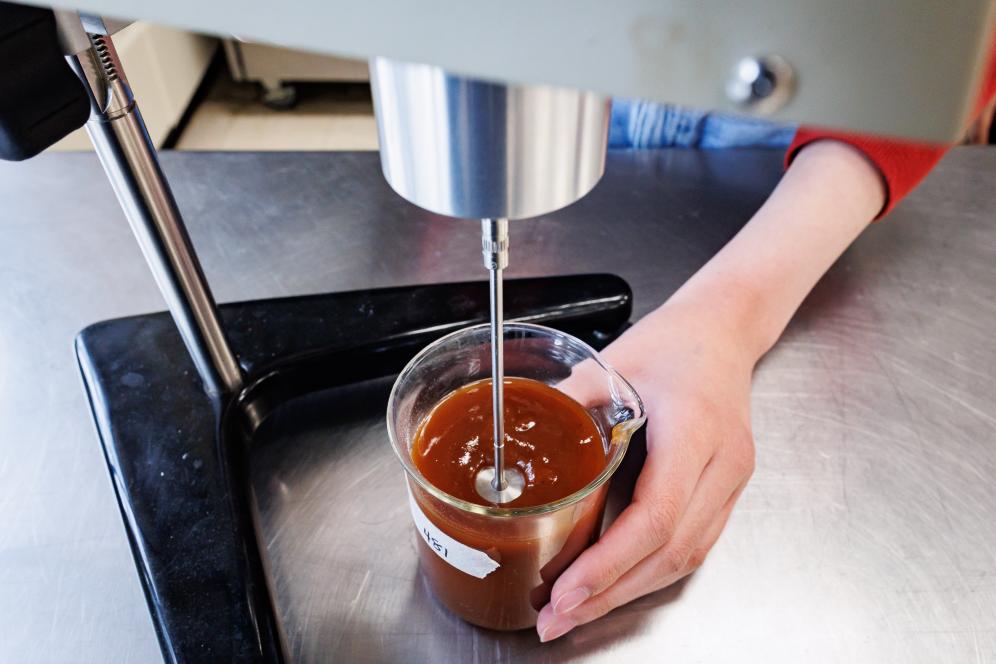 A student is using food science technology in the lab. This is a shot of hands only.